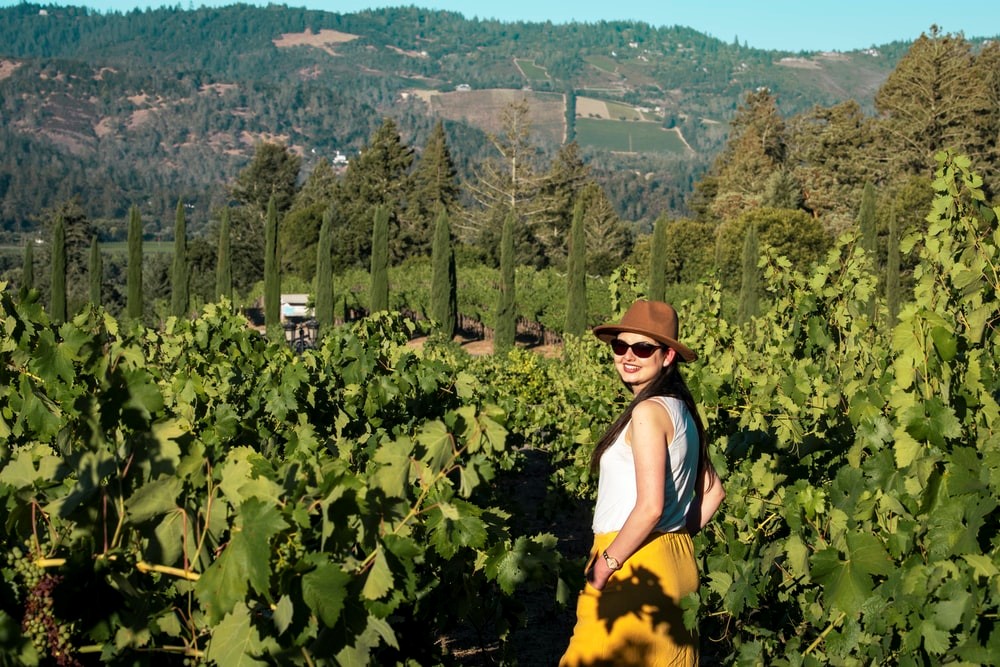 woman in blue tank top and yellow skirt standing on green plants during daytime